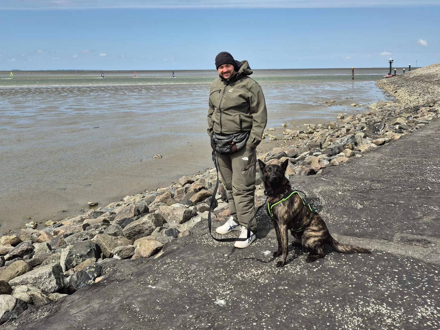 Jens Meyer steht mit seinem Hund Chewie am Wattenmeer